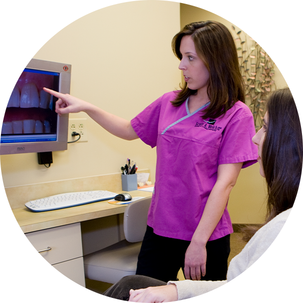 photo of dental assistant showing patient photos of her teeth on a computer screen